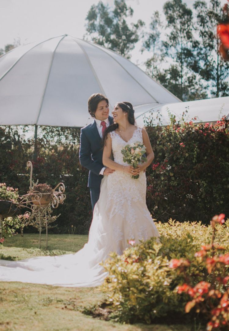 Novios abrazándose en su boda en una hacienda con un hermoso jardín.